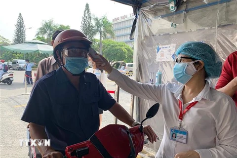 Đo thân nhiệt cho người dân đến khám bệnh tại Bệnh viện Thống Nhất Thành phố Hồ Chí Minh. (Ảnh: Đinh Hằng/TTXVN)