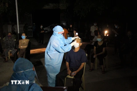 Lực lượng y bác sỹ xuyên đêm lấy mẫu xét nghiệm đối với các trường hợp là F1 của bệnh nhân số 11634 ở huyện Diễn Châu, Nghệ An. (Ảnh: Văn Tý/TTXVN)