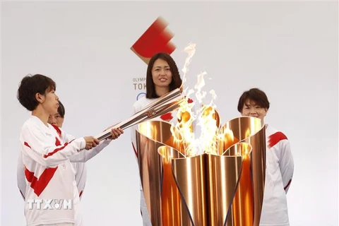 Vận động viên bóng đá Nhật Bản Azusa Iwashimizu (trái) thắp sáng ngọn đuốc Olympic tại lễ rước đuốc Olympic Tokyo 2020, ở Naraha, tỉnh Fukushima, Nhật Bản, ngày 25/3/2021. (Ảnh: AFP/ TTXVN)