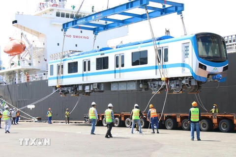 Toa xe đầu tiên của đoàn tàu số 4 được cẩu khỏi tàu vận chuyển Pulang Tala và đặt xuống xe chuyên dụng. (Ảnh: Tiến Lực/TTXVN)
