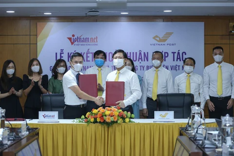 Tổng Biên tập Báo VietNamNet Phạm Anh Tuấn và Tổng Giám đốc Vietnam Post Chu Quang Hào ký thỏa thuận hợp tác. (CTV/Vietnam+)