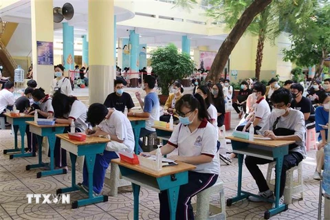 Học sinh ngồi giãn cách tại khu vực điền thông tin cá nhân trước khi vào lấy mẫu tại điểm Trường Tiểu học Nguyễn Bỉnh Khiêm (Quận 1). (Ảnh: Thu Hương/TTXVN)
