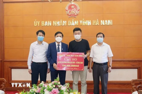 Tiếp nhận ủng hộ 100 triệu đồng từ Công ty TNHH may Kim Bình. (Ảnh: Nguyễn Chinh/TTXVN)