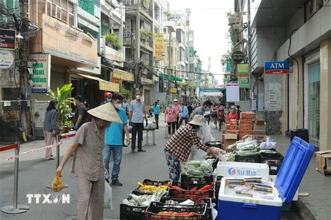 Người dân mua hàng hóa thiết yếu tại một Phiên chợ lưu động được tổ chức tại khu phố 3, phường 2, Quận 3, Thành phố Hồ Chí Minh. (Ảnh: Quang Châu/TTXVN)