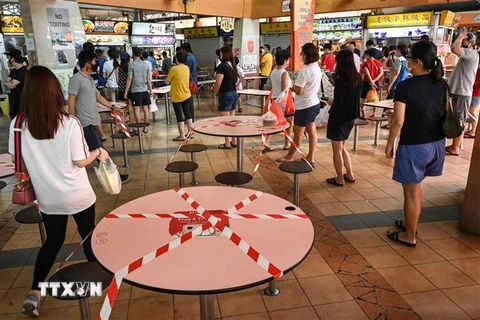 Người dân xếp hàng mua đồ ăn mang về để phòng lây nhiễm COVID-19 tại Singapore. (Ảnh: AFP/TTXVN)
