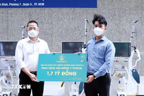 Đại diện Công ty Phú Long (trái) trao tặng Hội Đông y Thành phố Hồ Chí Minh 1,7 tỷ đồng. (Ảnh: Xuân Khu/TTXVN)