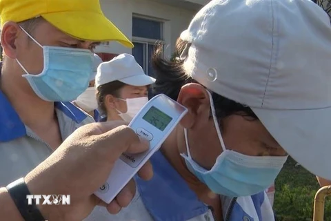 Công ty TNHH ắc quy CSB Việt Nam (KCN Nhơn Trạch 1, Đồng Nai) thực hiện đo kiểm tra thân nhiệt đối với mọi công nhân ra vào. (Ảnh: Công Phong/TTXVN)