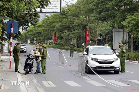 Lực lượng chức năng kiểm tra người đi đường trên phố Đào Tấn, quận Ba Đình ngày 23/8. (Ảnh: Trần Việt/TTXVN)