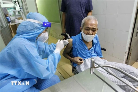 Các y bác sỹ bệnh viện Phú Nhuận thực hiện tiêm vaccine cho người trên 65 tuổi, người có bệnh nền tại Trung tâm y tế phường 11, quận Phú Nhuận. (Ảnh: Thanh Vũ/TTXVN)