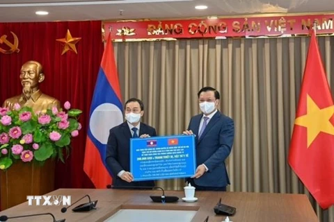 Bí thư Thành ủy Hà Nội Đinh Tiến Dũng trao quà tặng hỗ trợ Thủ đô Vientiane và 8 khu vực Bắc Lào để phòng, chống COVID-19. (Ảnh: TTXVN phát)