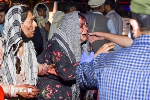 Nhân viên y tế hỗ trợ người bị thương trong vụ nổ bên ngoài sân bay quốc tế ở Kabul, Afghanistan. (Ảnh: AFP/TTXVN)