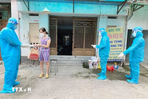 Nhân viên y tế trạm y tế lưu động phường 25, quận Bình Thạnh phát túi thuốc cho F0 điều trị tại nhà. (Ảnh: Đinh Hằng/TTXVN)