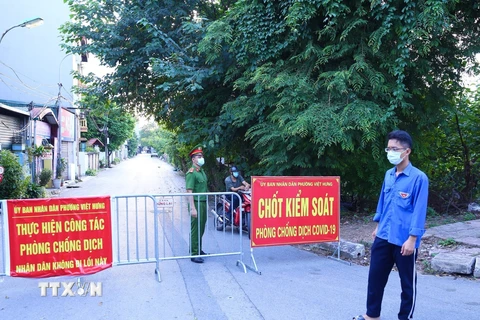 Lực lượng chức năng phường Việt Hưng chốt chặn các ngả đường để thực hiện nghiêm việc cách ly tạm thời. (Ảnh: Hoàng Hiếu/TTXVN)