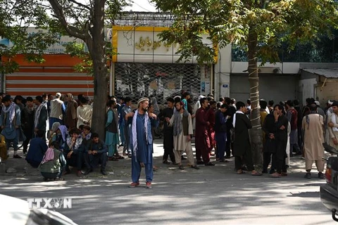 Người dân đợi bên ngoài một ngân hàng đóng cửa ở Kabul, Afghanistan, ngày 28/8. (Ảnh: AFP/TTXVN)