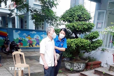 Giúp đỡ người dân đến tiêm vaccine tại điểm trường THCS Lương Khánh Thiện, Hà Nam. (Ảnh: Đại Nghĩa/TTXVN)