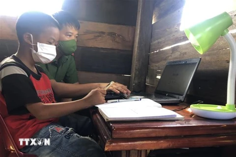 Thiếu tá Lê Anh Tuấn, Đội tổng hợp Công an huyện Cư M’Gar hướng dẫn học sinh có hoàn cảnh khó khăn sử dụng laptop do anh trao tặng. (Ảnh: TTXVN phát)