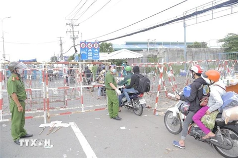Lực lượng công an phân luồng, đảm bảo an ninh trật tự tại khu vực người dân tập trung trên Quốc lộ 1, đoạn qua Thị trấn Tân Túc, huyện Bình Chánh, Thành phố Hồ Chí Minh. (Ảnh: TTXVN phát)