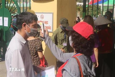 Người dân Quảng Ninh được đo thân nhiệt trước khi vào tiêm vaccine . (Ảnh: Thanh Vân/TTXVN)