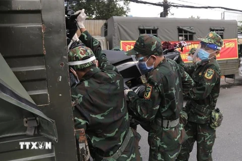 Lực lượng quân đội hỗ trợ vận chuyển xe máy cho người dân lên xe ôtô chở về quê. (Ảnh: TTXVN phát)