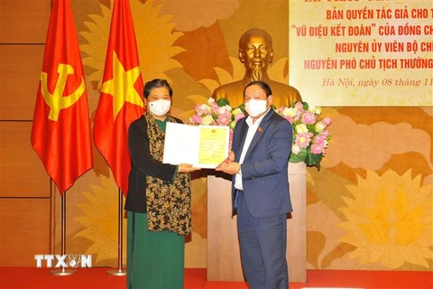 Nguyên Phó Chủ tịch thường trực Quốc hội Tòng Thị Phóng tiếp nhận Giấy chứng nhận đăng ký bản quyền tác giả. (Ảnh: Minh Đức/TTXVN)