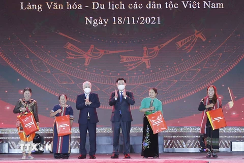 Chủ tịch Quốc hội Vương Đình Huệ và Chủ tịch Ủy ban Trung ương Mặt trận Tổ quốc Việt Nam Đỗ Văn Chiến trao quà cho các đại biểu dân tộc tại Làng Văn hóa. (Ảnh: Doãn Tấn/TTXVN)
