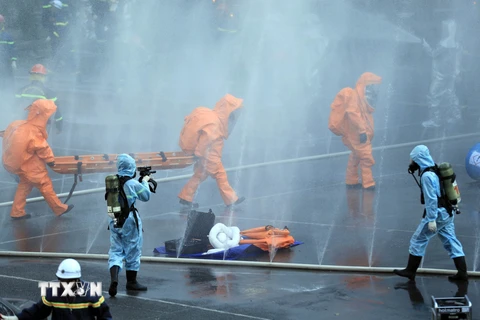 Lực lượng Phòng cháy chữa cháy và cứu nạn cứu hộ thực hiện ngăn chặn sự phát tán của hóa chất nguy hiểm đến khu vực xung quanh. (Ảnh: Phạm Kiên/TTXVN)