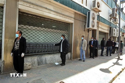 Người dân xếp hàng trước một ngân hàng ở Tripoli, Libya. (Ảnh: AFP/TTXVN)