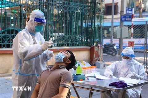 Nhân viên y tế lấy mẫu xét nghiệm sàng lọc COVID-19 cho người dân trong khu vực bị phong tỏa tại Hà Nội. (Ảnh minh họa: Hoàng Hiếu/TTXVN)
