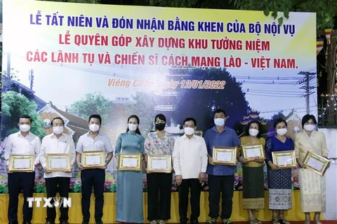 Bộ trưởng Nội vụ Lào, ông Thongchan Manixay (giữa) với các cá nhân và tập thể người Việt có nhiều thành tích trong công tác cứu trợ và vận động cứu trợ cho người dân Lào gặp thiên tai, dịch bệnh trong thời gian qua. (Ảnh: Phạm Kiên/TTXVN)