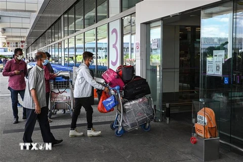 Hành khách đeo khẩu trang phòng dịch COVID-19 tại sân bay quốc tế Changi, Singapore. (Ảnh: AFP/ TTXVN)
