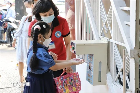 Học sinh trường tiểu học Hoà Bình (Quận 1) được giáo viên hướng dẫn rửa tay trước khi vào lớp. (Ảnh: Hồng Giang/TTXVN)