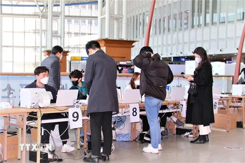 Các cử tri xuất trình giấy tờ tùy thân, chờ nhận phiếu bầu từ ban tổ chức. (Ảnh: Khánh Vân/ TTXVN)