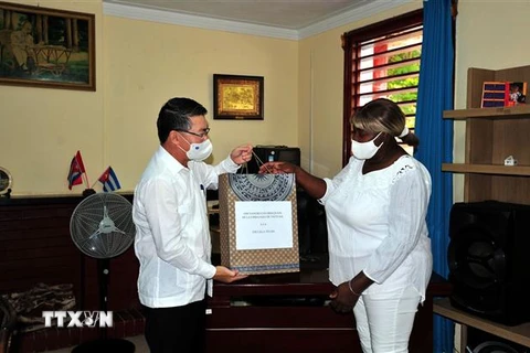 Đại sứ Việt Nam tại Cuba Lê Thanh Tùng trao quà tượng trưng cho Hiệu trưởng trường tiểu học “Bác Hồ” Milagros Negret Calderín. (Ảnh: Vũ Lê Hà/TTXVN)