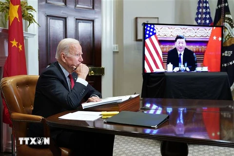 Tổng thống Mỹ Joe Biden (trái) điện đàm với Chủ tịch Trung Quốc Tập Cận Bình (ảnh trên màn hình), ngày 15/11/2021. (Ảnh: AFP/TTXVN)