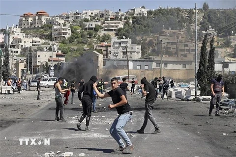 Người biểu tình Palestine ném đá về phía cảnh sát Israel trong cuộc đụng độ tại khu vực Đền Al-Aqsa ở Đông Jerusalem ngày 15/4. (Ảnh: AFP/TTXVN)