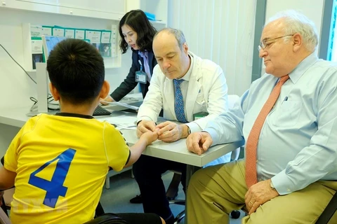 Bác sỹ Stéphane Guero (giữa) khám cho một bệnh nhi bị dị dạng ngón tay. (Ảnh: TTXVN phát)