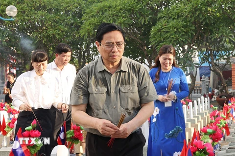 Thủ tướng Phạm Minh Chính thắp hương trên phần mộ liệt sỹ tại Nghĩa trang liệt sỹ quốc tế Việt - Lào. (Ảnh: Dương Giang/TTXVN)