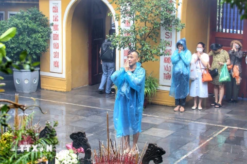 Người dân thành tâm cầu khấn tại chùa Quán Sứ dù trời mưa to. (Ảnh: Tuấn Đức/TTXVN)
