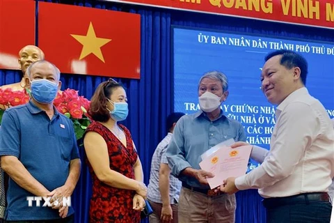 Chủ tịch Ủy ban Nhân dân thành phố Thủ Đức Hoàng Tùng (bên phải) trao Giấy chứng nhận quyền sử dụng đất, nhà ở cho người dân. (Ảnh: Hồng Giang/TTXVN)