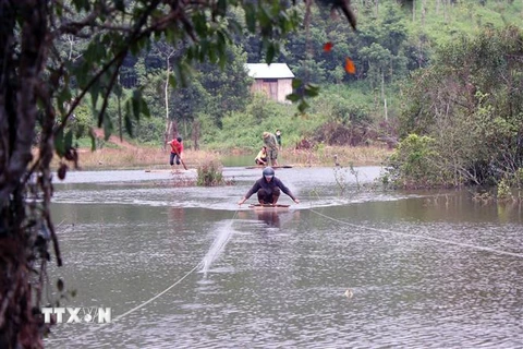 Người dân “chế” bè qua sông sau khi con đường ngang suối bị xóa sổ. (Ảnh: Hưng Thịnh/TTXVN)