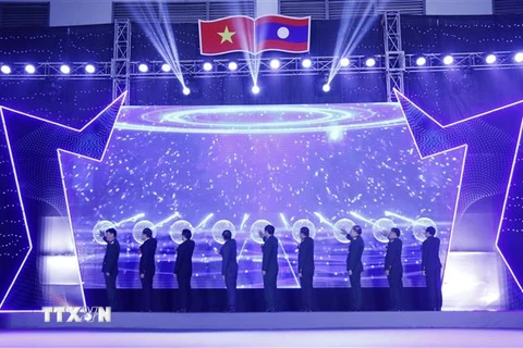 Lãnh đạo các bộ ngành liên quan của hai nước và Đại sứ Việt Nam tại Lào Nguyễn Bá Hùng nhấn nút khai mạc Hội chợ thông qua ứng dụng tương tác trên màn hình LED. (Ảnh: Phạm Kiên/TTXVN)