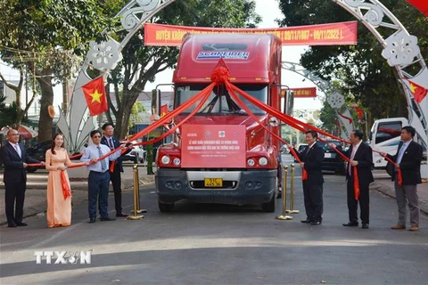 Các đại biểu thực hiện nghi thức kéo dải lụa đỏ cho xe chạy xuất khẩu container macca Krông Năng đầu tiên. (Ảnh: Hoài Thu/TTXVN)