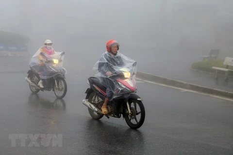 Người dân thị xã Sapa mặc áo mưa tránh rét. (Ảnh: Quốc Khánh/TTXVN)