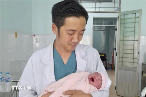 Bác sỹ Lê Nguyễn Linh, Trưởng Khoa Phụ sản Bệnh viện Đa khoa khu vực Định Quán và bé gái. (Ảnh: TTXVN phát) 