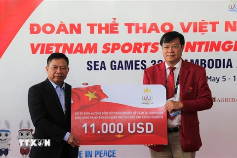 Đại sứ Nguyễn Huy Tăng (trái) tặng quà, chúc mừng Đoàn thể thao Việt Nam. (Ảnh: Hoàng Minh/TTXVN)