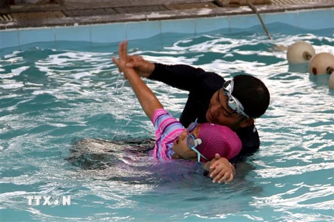 Các thầy, cô dạy học sinh kỹ năng bơi. (Ảnh: Trịnh Bang Nhiệm/TTXVN)