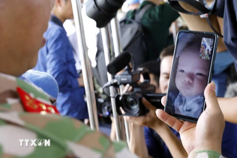 Cuộc điện thoại chào tạm biệt con nhỏ 4 tháng tuổi của một chiến sỹ công binh trước giờ lên đường làm nhiệm vụ. (Ảnh: An Đăng/TTXVN)