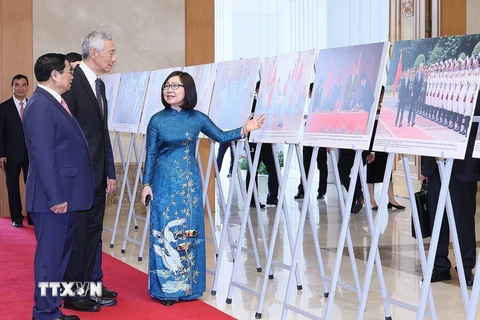 Phó Tổng Giám đốc TTXVN Đoàn Thị Tuyết Nhung giới thiệu với Thủ tướng Phạm Minh Chính và Thủ tướng Lý Hiển Long hình ảnh về quá trình hợp tác giữa Việt Nam và Singapore.