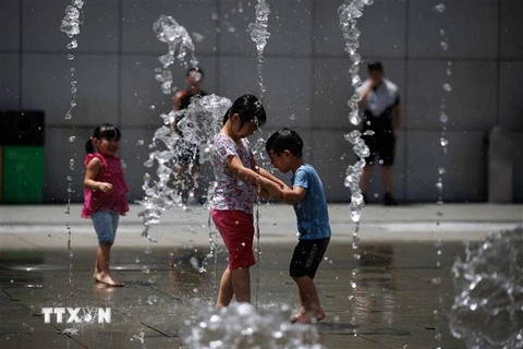 Trẻ em giải nhiệt tránh nóng tại một đài phun nước ở Hong Kong, Trung Quốc. (Ảnh: AFP/TTXVN)