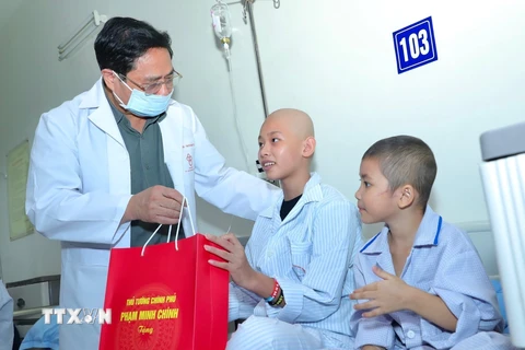 Thủ tướng Phạm Minh Chính động viên và tặng quà cho bệnh nhi đang điều trị nội trú tại Viện Huyết học và Truyền máu Trung ương. (Ảnh: Hoàng Hiếu/TTXVN)